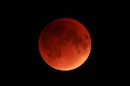 A bright red Moon during a total lunar eclipse against a black night sky.
