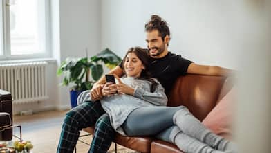 A couple with mobile phone relaxing on sofa