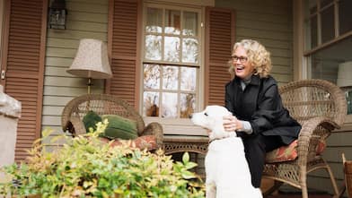 A woman sitting on porch rocking chair with dog