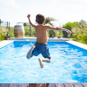 A boy jumping in a pool happily on a sunny day