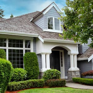 A house with a cedar shake roof and lush gardens