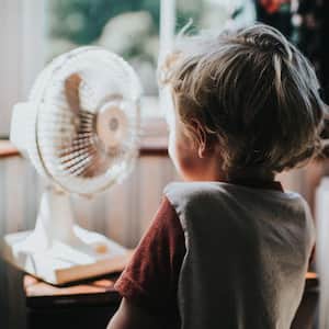 A boy standing in front of a fan