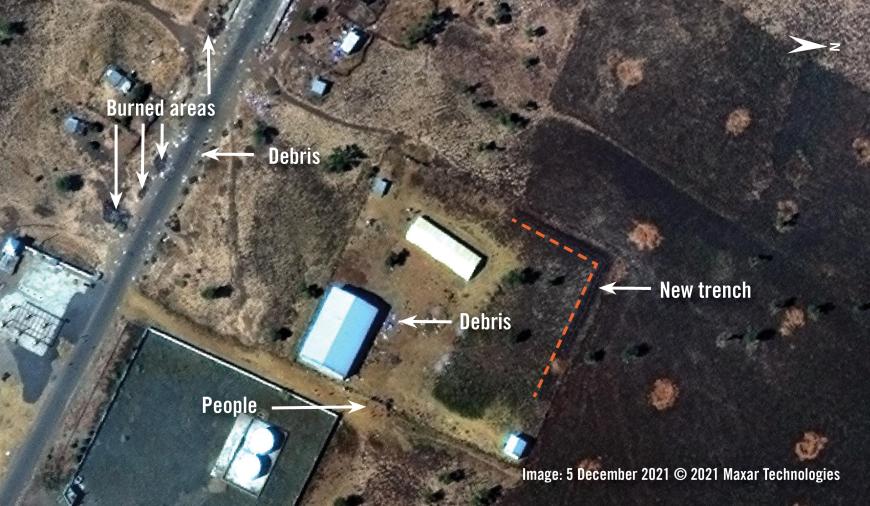 Analysis of satellite image collected on 5 December 2021 of the eastern outskirts of Adebai town. People and debris are visible around a large warehouse, near the Enda Roto petrol station. Burned areas and debris are visible by the main road.  © Analysis by Amnesty International; satellite image courtesy of Maxar Images. 2021