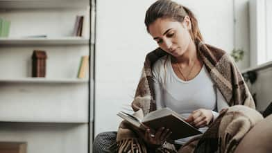 Girl reads a book while wrapped in a blanket