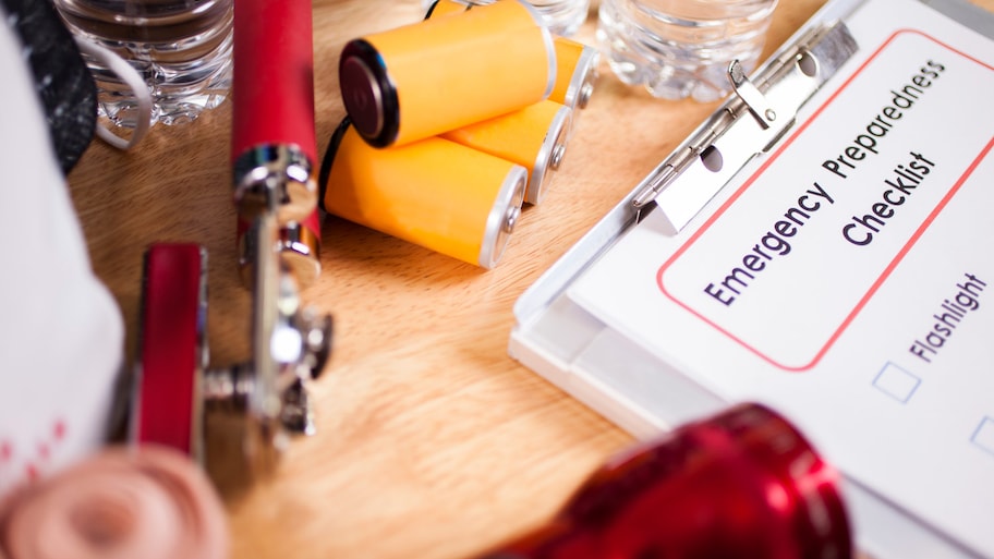 Detail photo of an emergency checklist, flashlight, batteries and water bottles