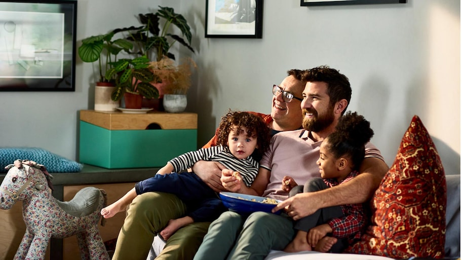 Two fathers and their children watch tv in basement