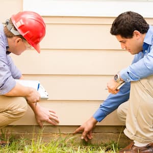 Two professionals inspecting house foundation