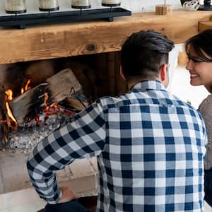 A couple burns logs in fireplace of cabin