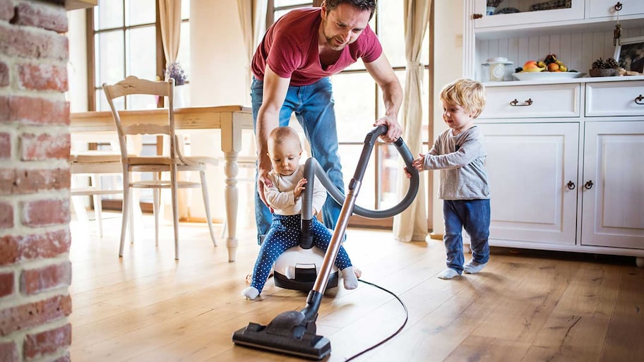 Father vacuuming with children