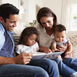 A family of four seating on the sofa reading a book