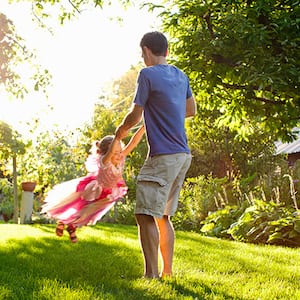 Fathers swings daughter under trees