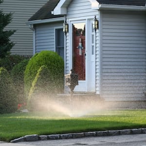 house with sprinklers watering front lawn