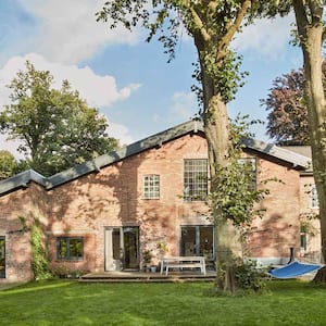 Large brick house surrounded by tall trees