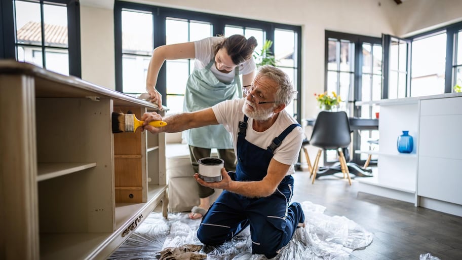 Father and daughter painting together some old furniture