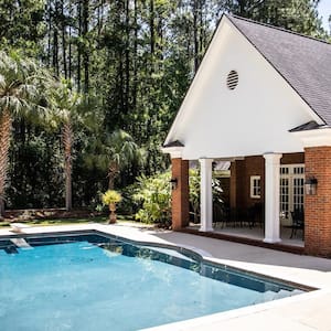 A luxurious pool house behind a house’s swimming pool