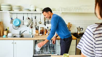 A man putting coffee mugs into dishwasher