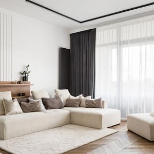 A bright living room with a tall windows and beautiful long curtains