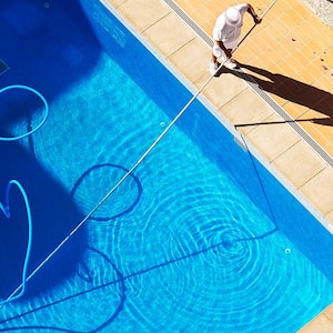 A man cleans a swimming pool