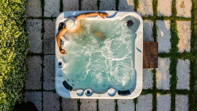 Man in hot tub stones grass overhead