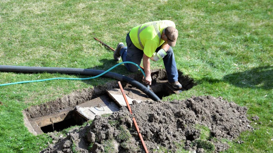 A worker pumping out a backyard septic tank