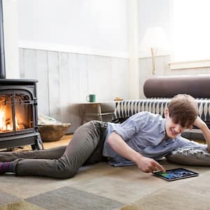 Man lays in front of cozy fire in wood-burning stove