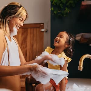 A mother and daughter wash dishes