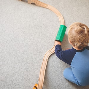 Toddler playing with train on carpet