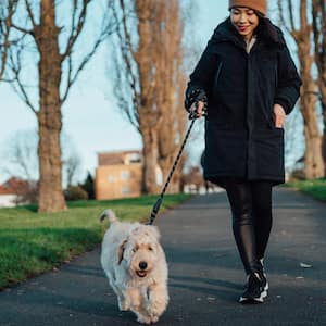 A young woman walking her dog in the park