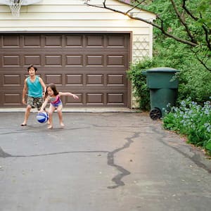 Kids play ball on asphalt drive