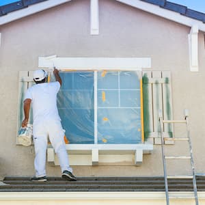 House painter painting the trim and shutters of home