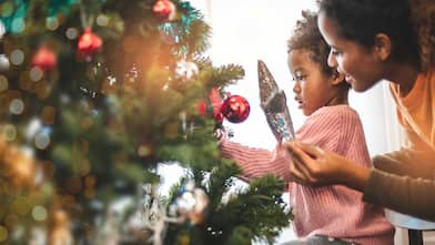 A mother and child decorate a Christmas tree