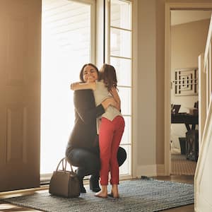 Woman greets little girl at front door