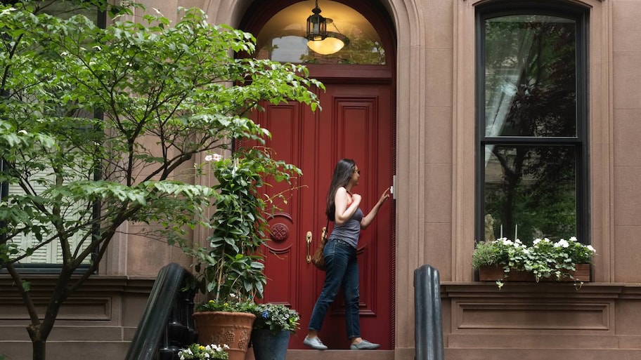 Woman ringing doorbell in front of red door