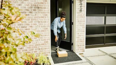 Woman picking up package at front door