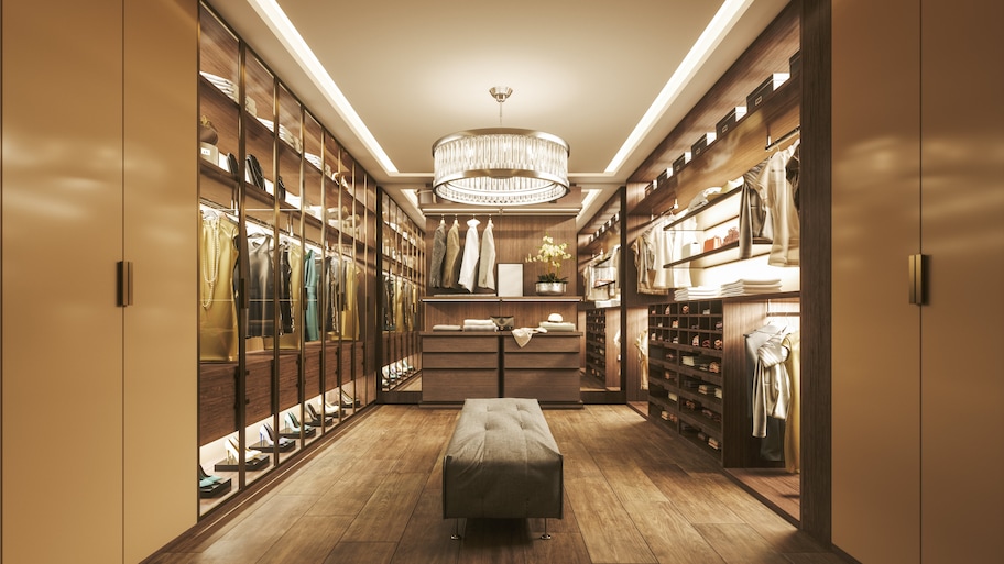 A long walk-in closet with a lit chandelier hanging from the ceiling 