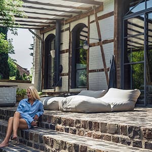 Woman sitting on porch steps outside a painted brick home