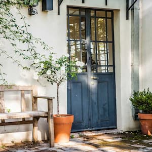 A blue french door and two wooden benches in a house’s patio