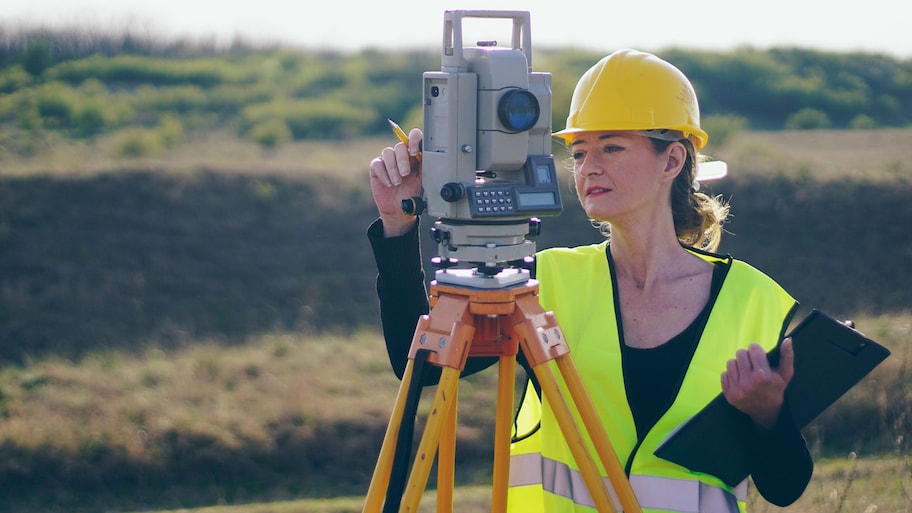 Female land surveyor using equipment to measure land