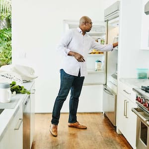 Man in the kitchen putting groceries in the refrigerator