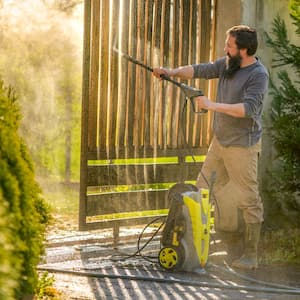 A man cleaning a wooden gate using a pressure washer