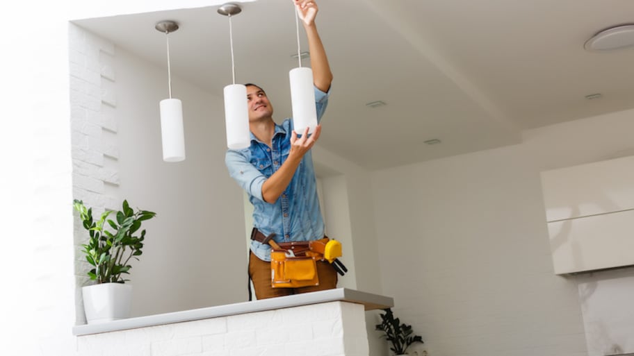 man with tool belt installing hanging lights 