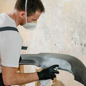 A man spray paints an object black