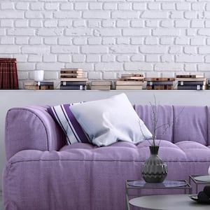 A purple sofa in a living room with white painted exposed brick wall