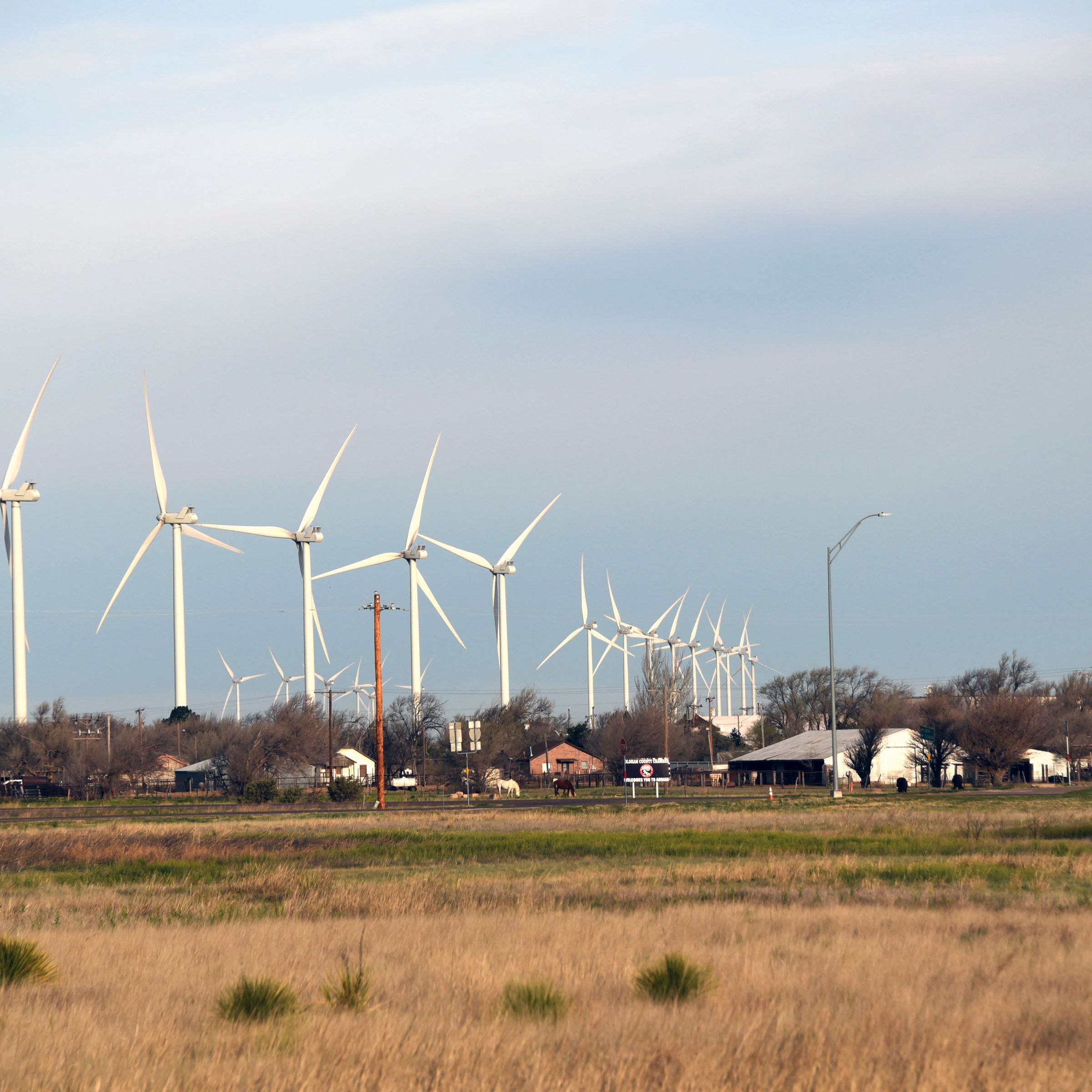 Wind turbines stand behind homes