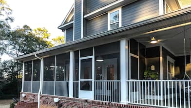 Blue two-story house with screened-in wrap around porch