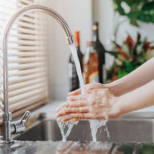 A woman testing the water temperature of the kitchen sink