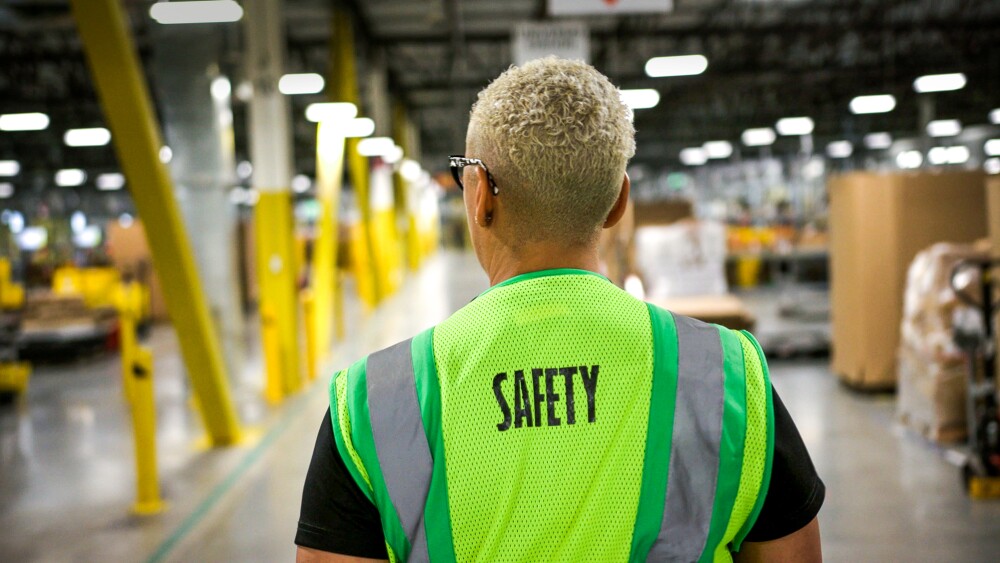 Person in a safety vest walks through a warehouse