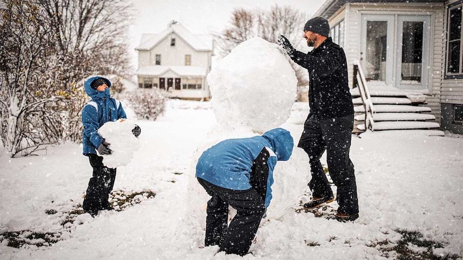 A father and sons build a snowman