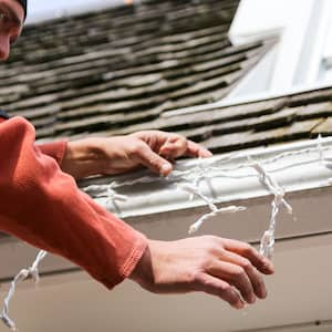 man installing Christmas lights on roof