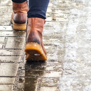 Person walking on pavement with melting snow